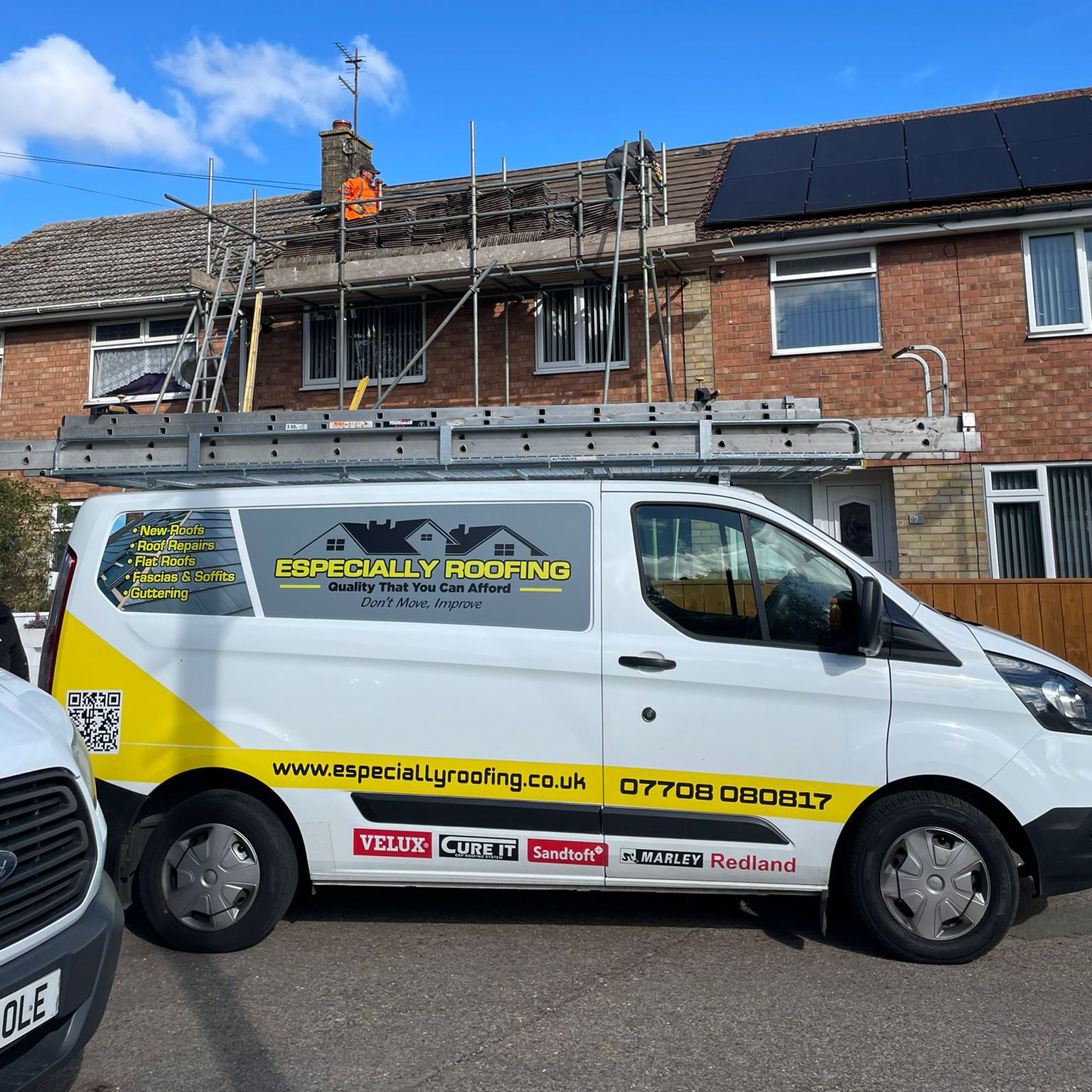A white van with a yellow logo reading "Especially Roofing" is parked in front of a brick house under renovation. Scaffolding surrounds the new roof as a worker in an orange vest works diligently. A clear blue sky provides the perfect backdrop for installing replacement guttering.